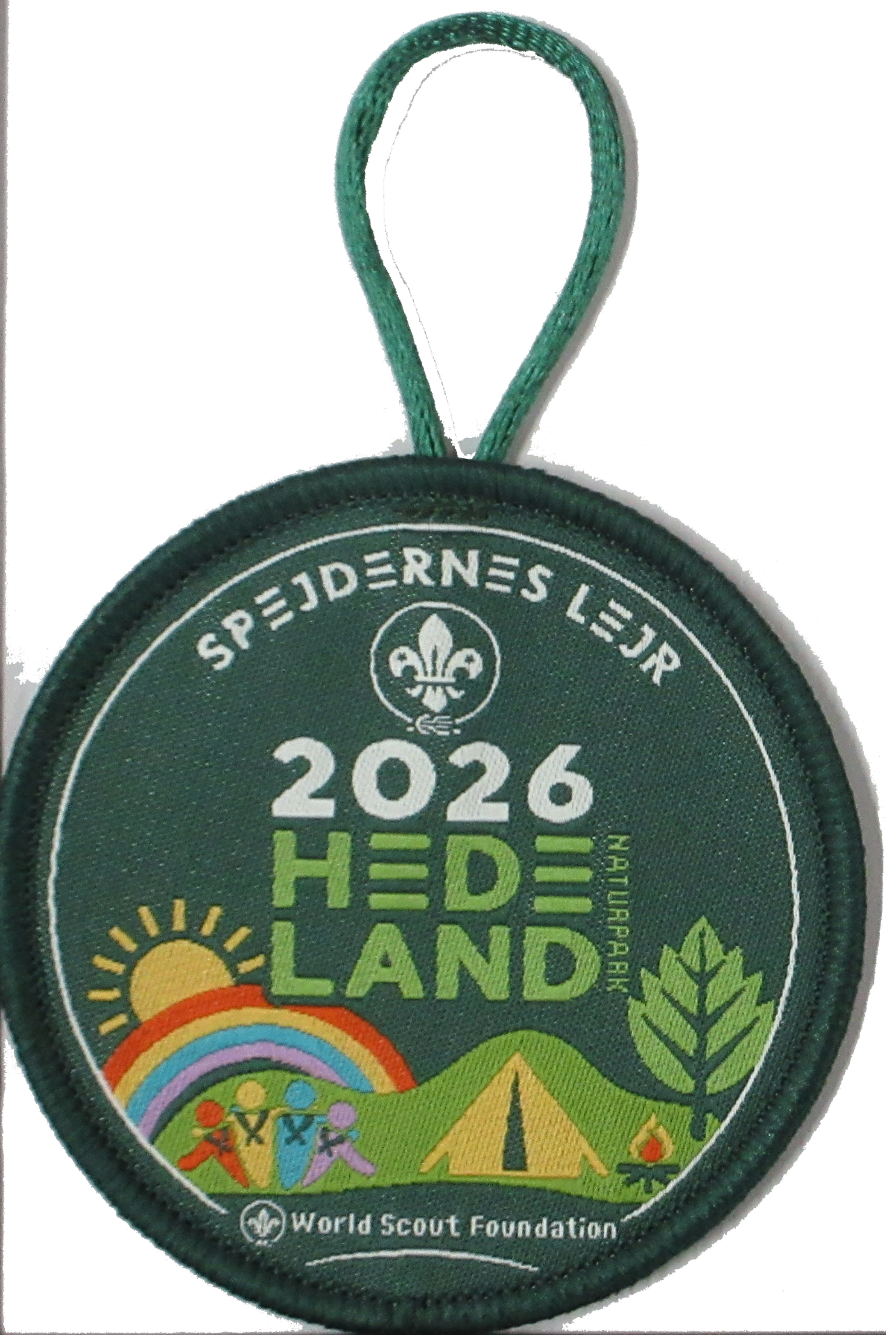 Vævet rundt mærke 'Spejdernes Lejr 2026 Hedeland Naturpark' med grøn kant og snor
